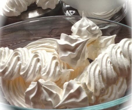 Meringues suisses blanches dressées en rosaces dans un saladier en verre