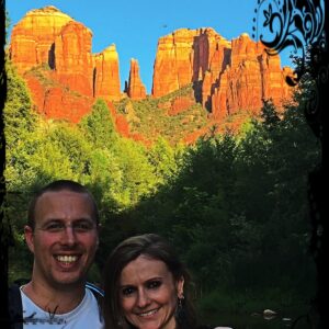 Souvenir du voyage : couple devant des formations de roches rouges bordées d’arbres