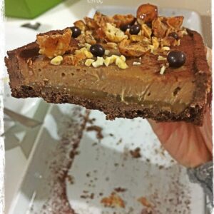 Part de tarte Biskélia, caramel et noisette tenue à la main
