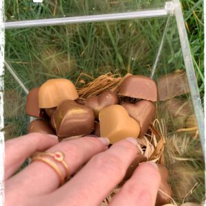 Chocolats en forme de cœur dans une boîte avec une main visible