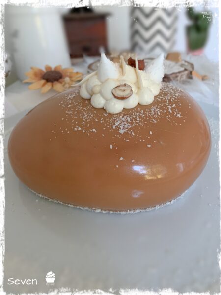 Gros plan sur l’entremets Seven au glaçage caramel et son décor blanc