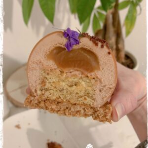 Entremets American Dream coupé montrant l’insert caramel tenu à la main