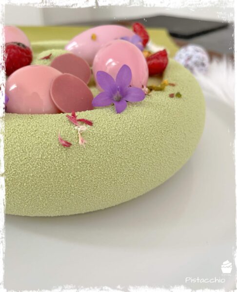 Gros plan sur l’entremets Pistacchio vert et son décor rose