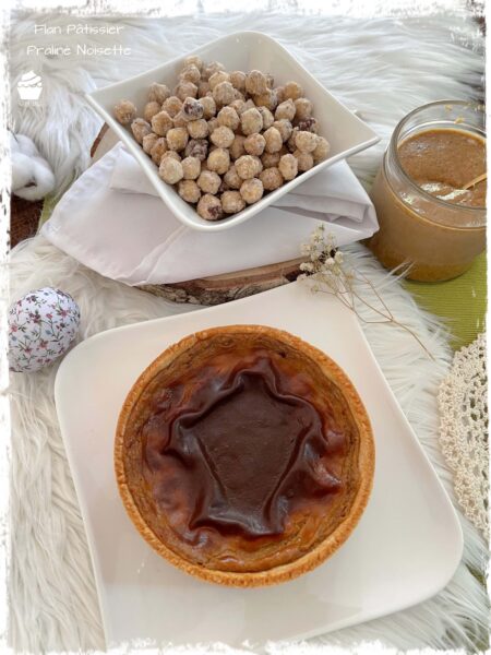 Flan pâtissier près de noisettes sablées et d’un bocal de praliné