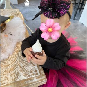 Enfant déguisé en sorcière tenant un cupcake fantôme