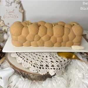 Bûche Bientôt 4 entière sur un plat devant un décor de Noël