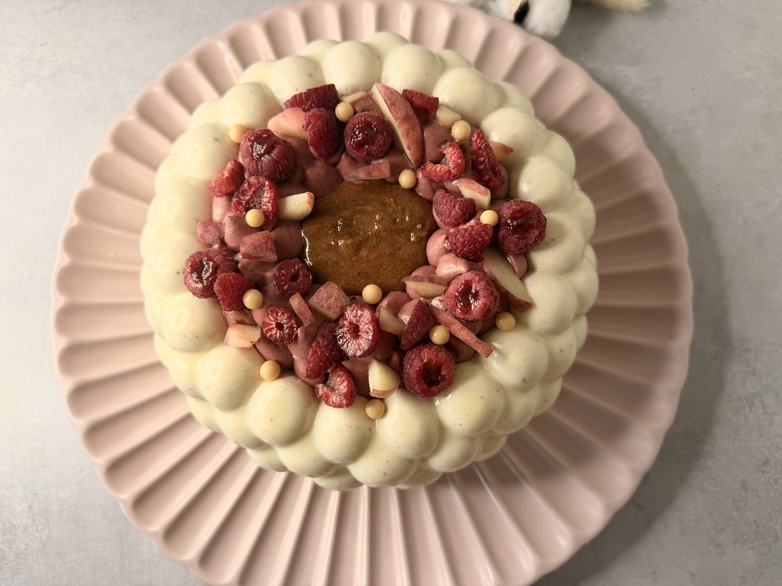 Entremets Melba et son décor de pêches et framboises vus du dessus